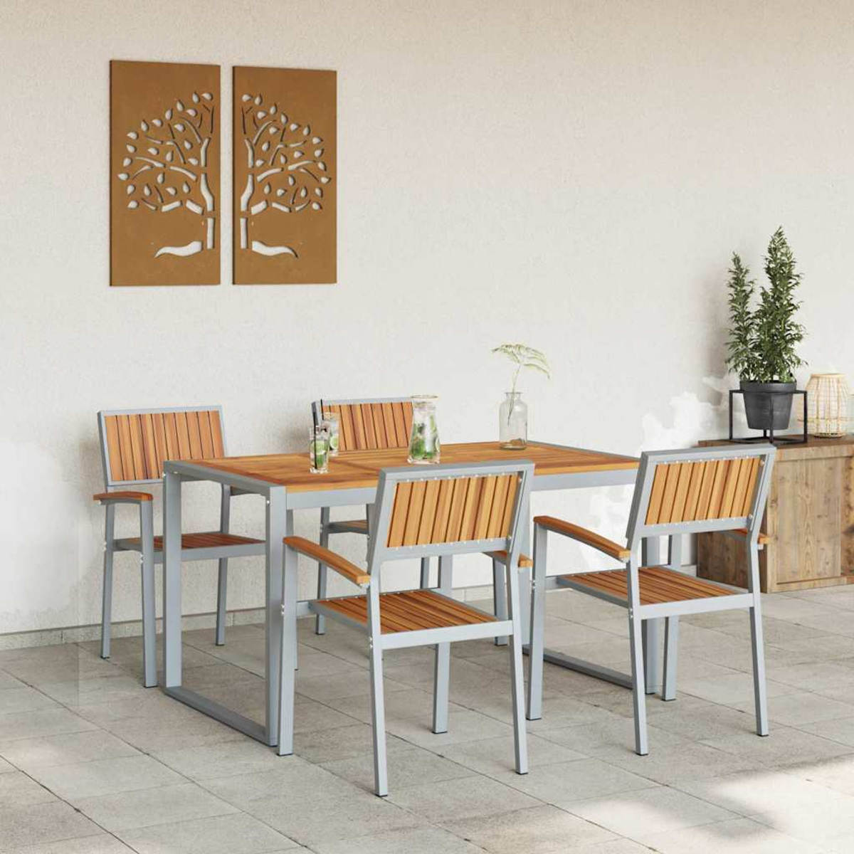 Essgruppe im Freien. Holztisch und -stühle, graue Rahmen. Braune Wanddekoration, zwei Baum-Ausschnitte. Pflanzen rechts.