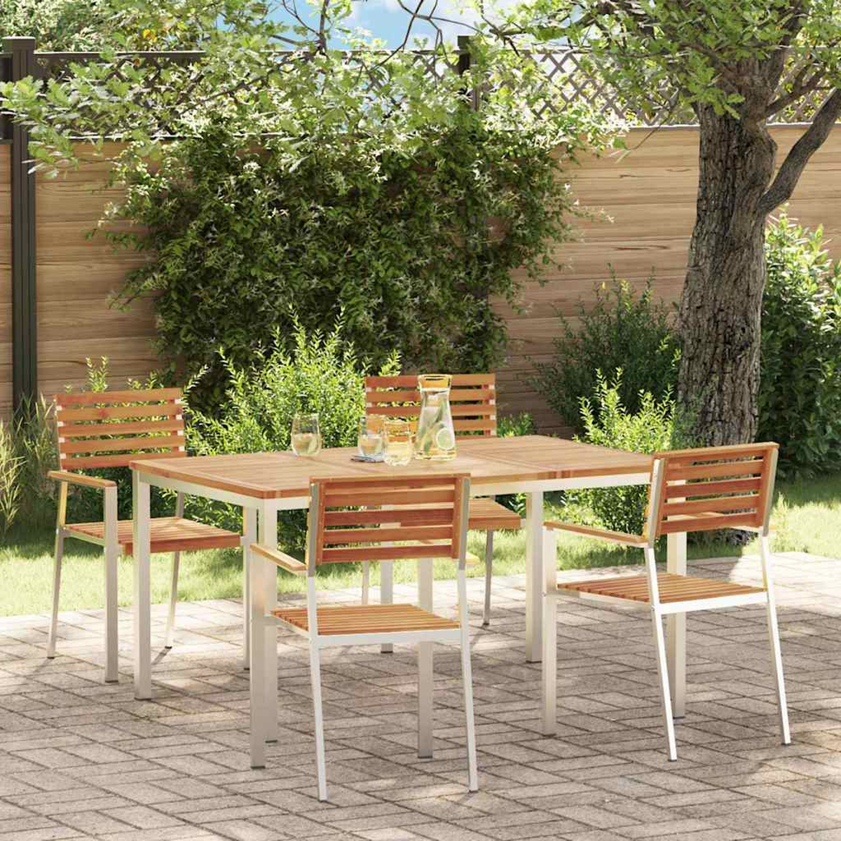 Essgruppe im Freien: Holztisch und Stühle auf einer Terrasse. Der Hintergrund umfasst eine üppige grüne Hecke und einen Baum.