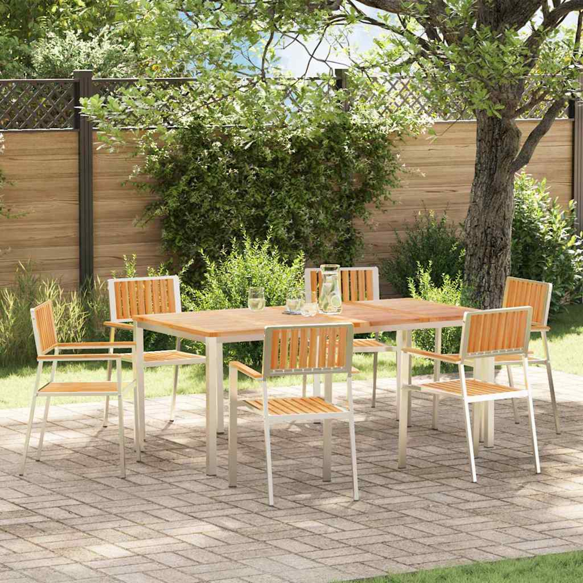 Essgruppe im Freien auf einer Ziegelterrasse. Holztisch und Stühle. Grünes Laub und Holzzaun im Hintergrund.