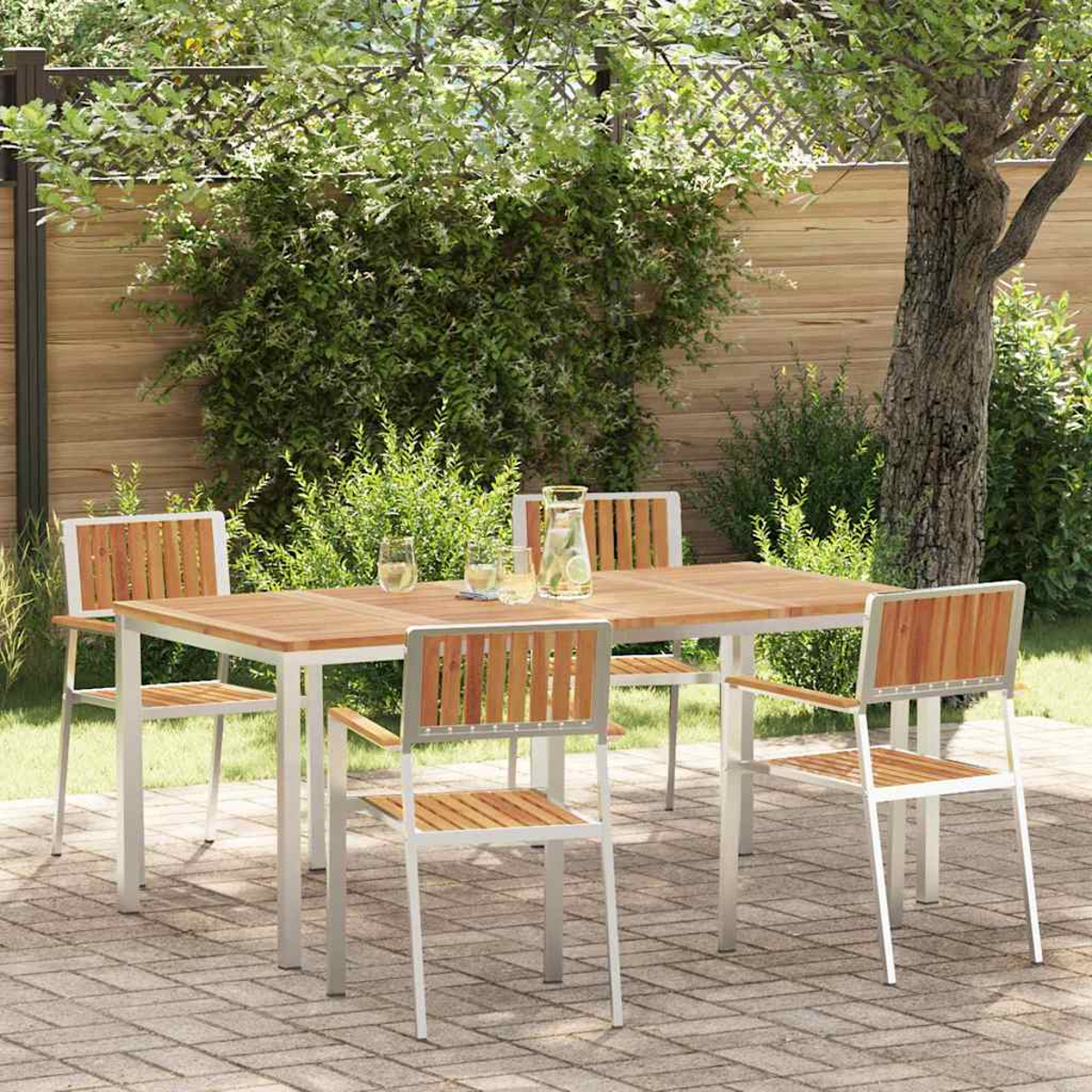 Essgruppe im Freien: Holztisch und Stühle auf einer Ziegelterrasse. Hintergrund: Holzzaun, Grün und Baum.