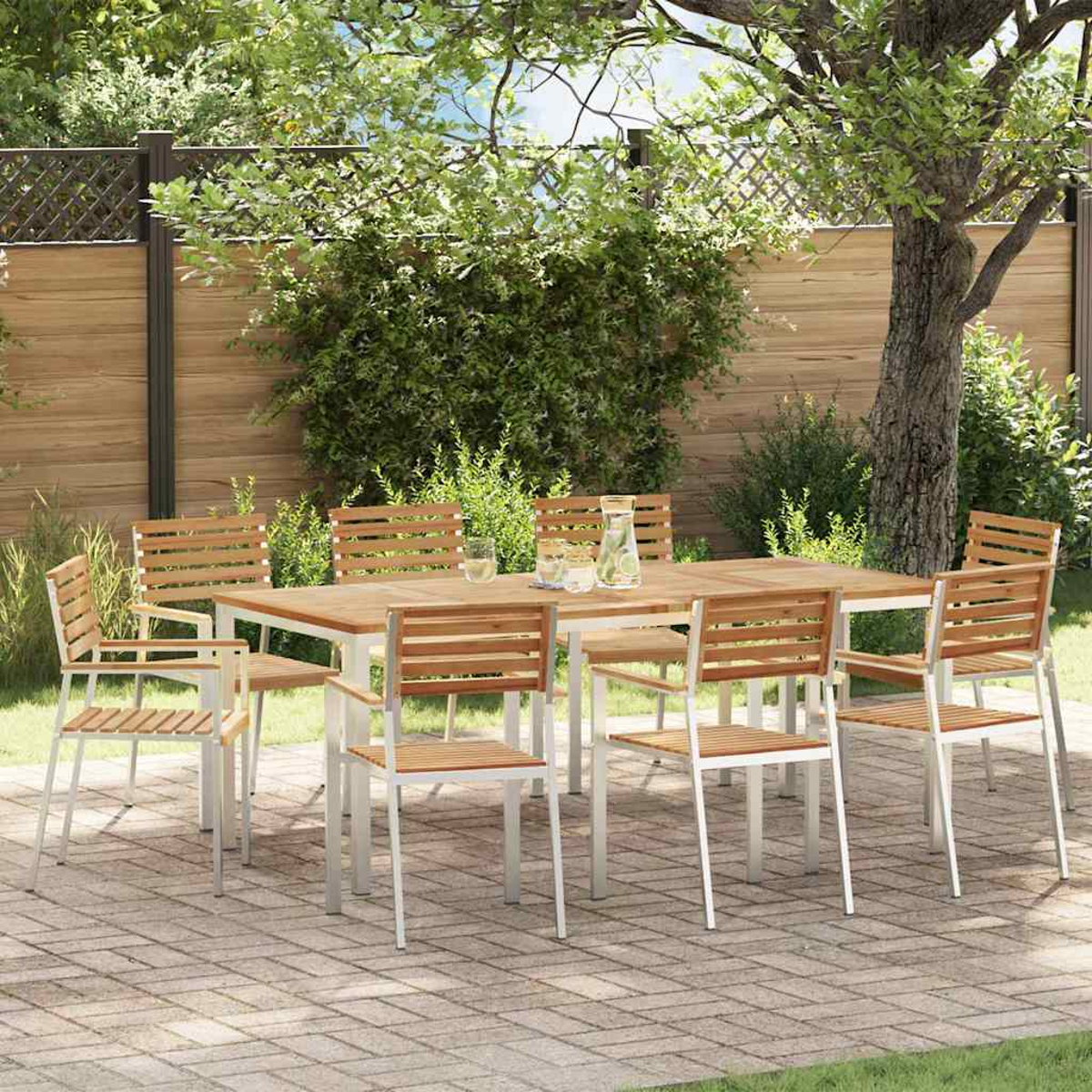 Essgruppe im Freien mit einem Holztisch und Stühlen auf einer Ziegelterrasse, umgeben von Grün und einem Holzzaun.