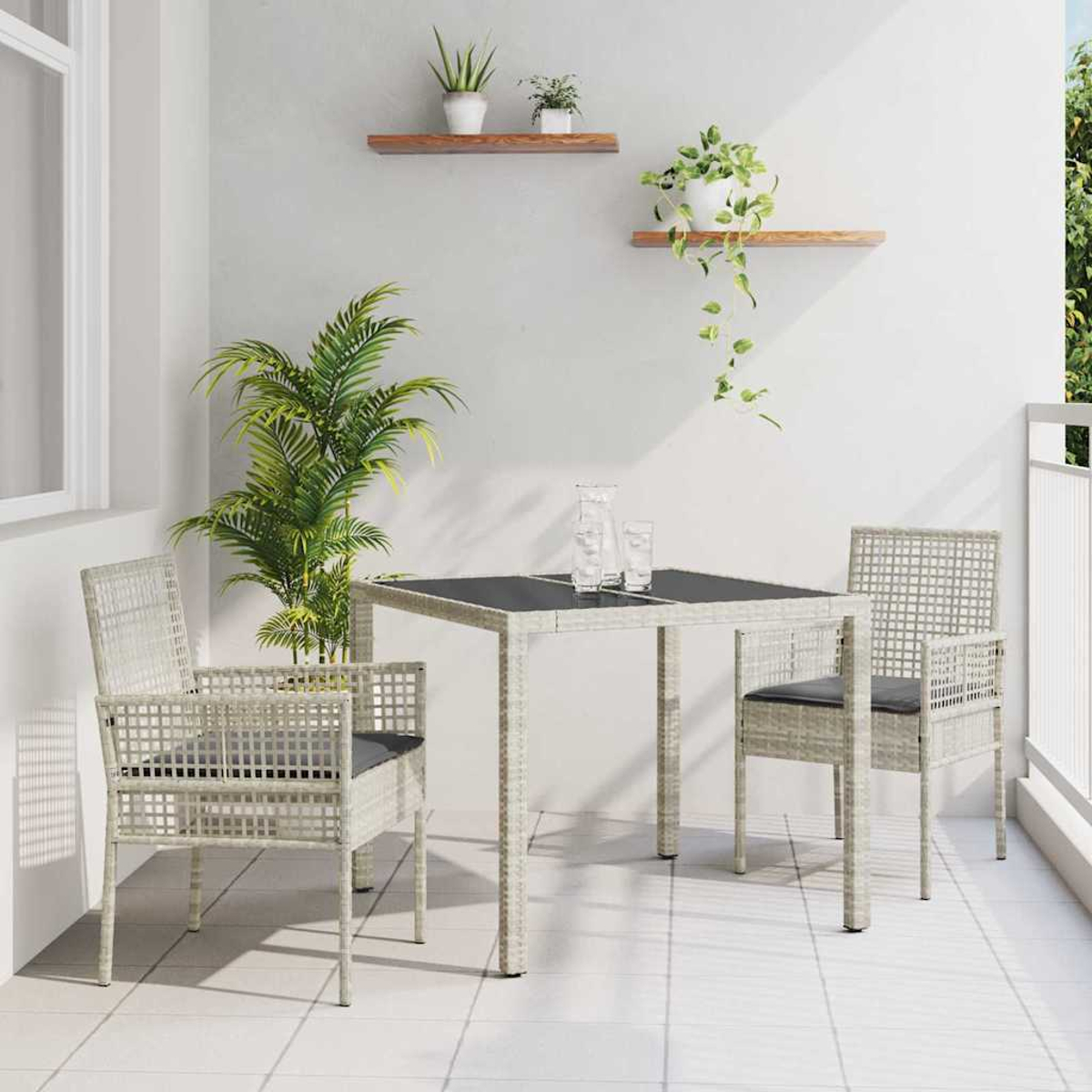 Balkonszene mit Tisch, Stühlen, Pflanzen und Regalen. Der Tisch hat eine dunkle Oberfläche. Stühle haben graue Kissen. Weiße Wände und Boden.
