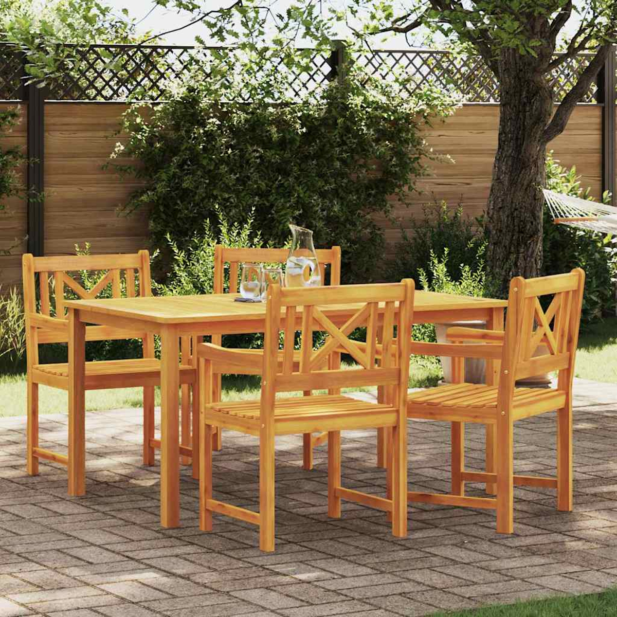 Essgruppe aus Holz im Freien: Tisch und Stühle auf einer Ziegelterrasse. Auf dem Tisch stehen ein Krug und Gläser, im Hintergrund ein Garten.