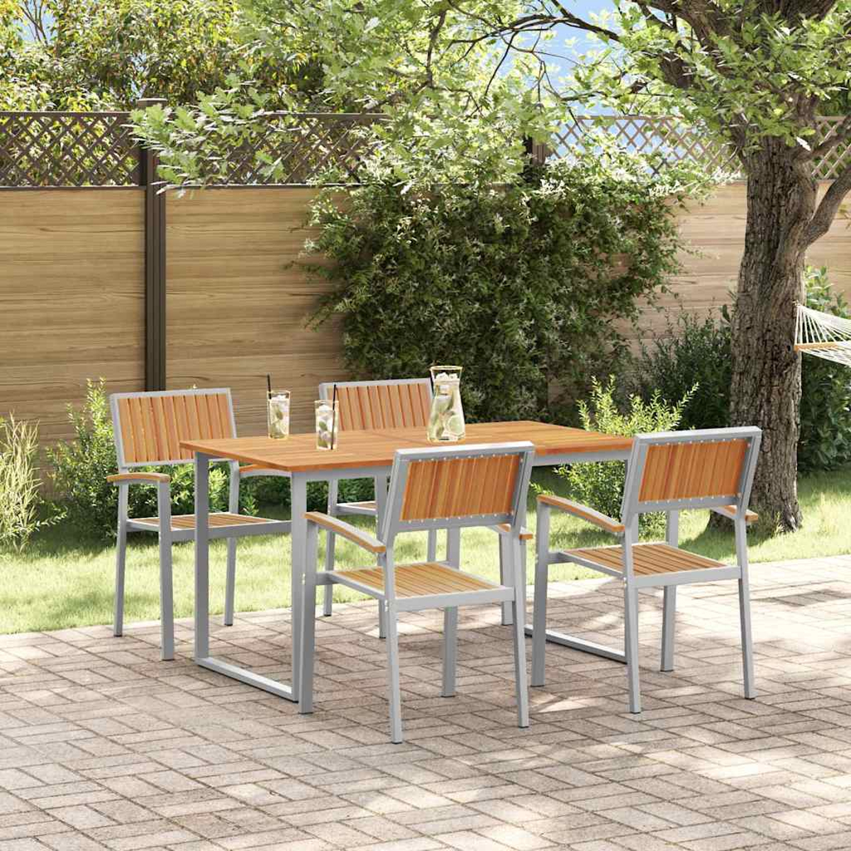 Holztisch und Stühle im Garten. Getränke auf dem Tisch, eine Hängematte und ein Holzzaun im Hintergrund.