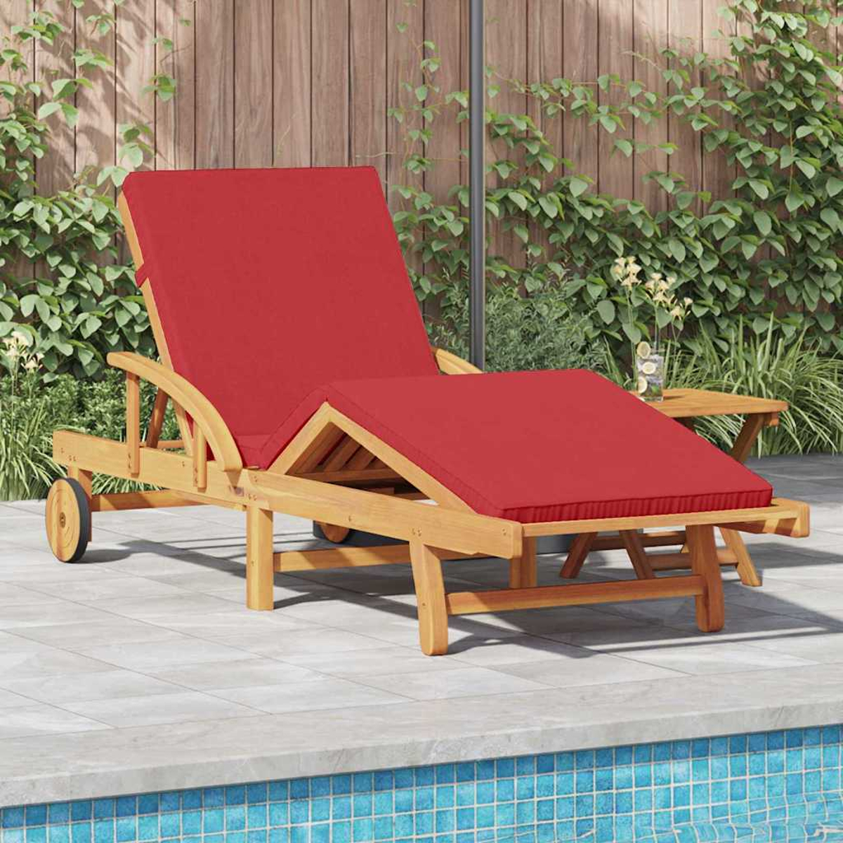 Eine Holzliege mit rotem Kissen am Pool. Im Hintergrund Holzlattenzaun, Pflanzen und ein kleiner Tisch.