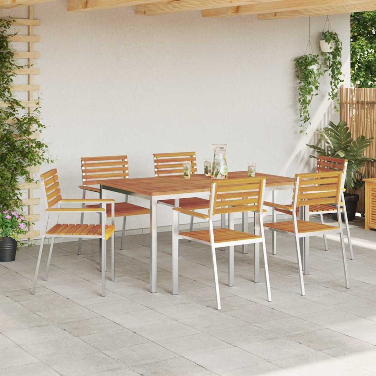Essgruppe im Freien mit Holztisch und Stühlen. Pflanzen und eine Wasserkaraffe stehen auf dem Tisch. Die Szene spielt auf einer Terrasse.