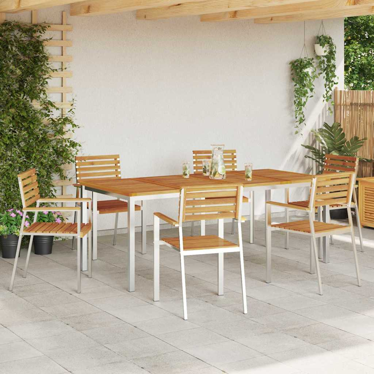 Essgruppe im Freien. Holztisch und Stühle mit Metallbeinen. Pflanzen in Töpfen und zum Aufhängen. Weiße Wand und Betonboden.