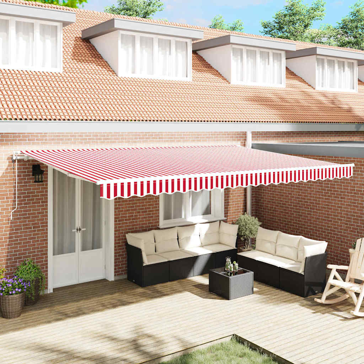 Eine Gartenszene mit rot-weiß gestreifter Markise, Sitzecke mit Sofas, Holzterrasse, Backsteinmauer und Haus mit Fenstern.