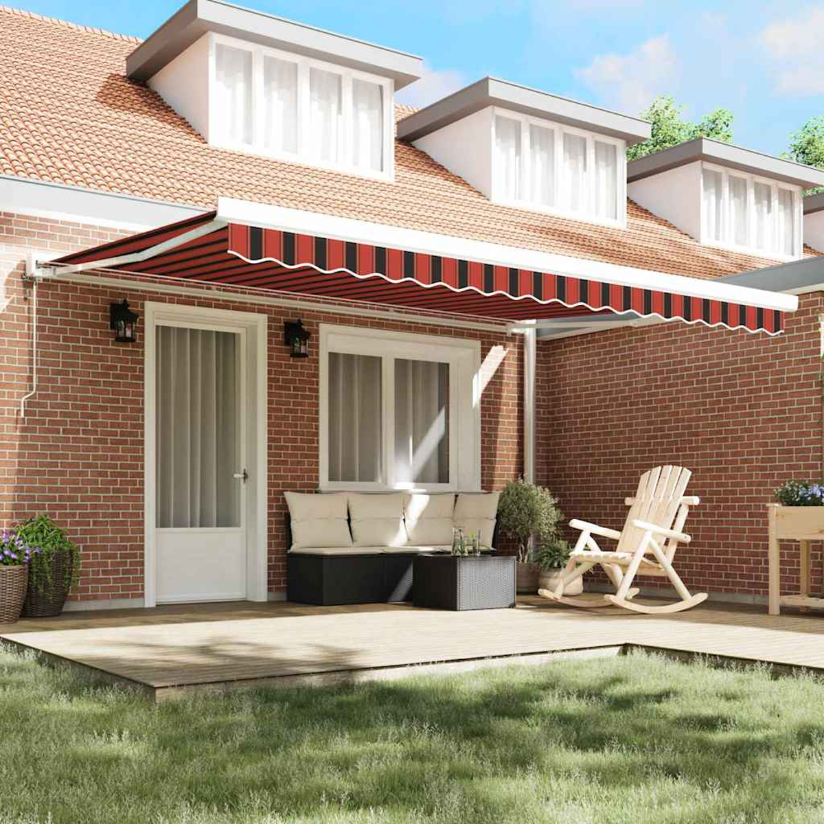 Una casa con fachada de ladrillo rojo, un toldo a rayas rojas y blancas y una terraza de madera con muebles de exterior. Un jardín de césped en frente.