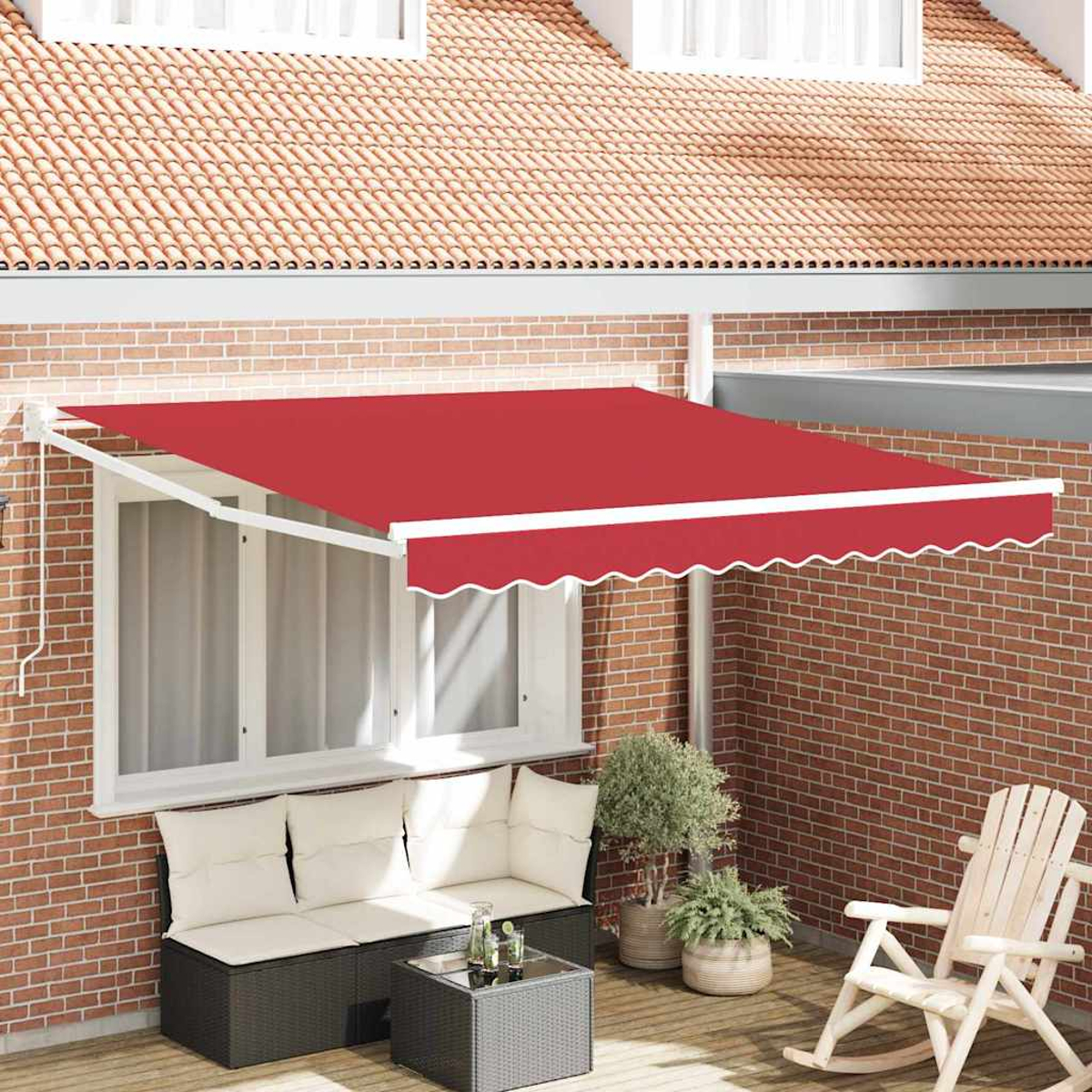 Rote Markise über einer Terrasse. Ein weiß gerahmtes Fenster, eine Backsteinmauer und eine Sitzecke mit Schaukelstuhl sind zu sehen.