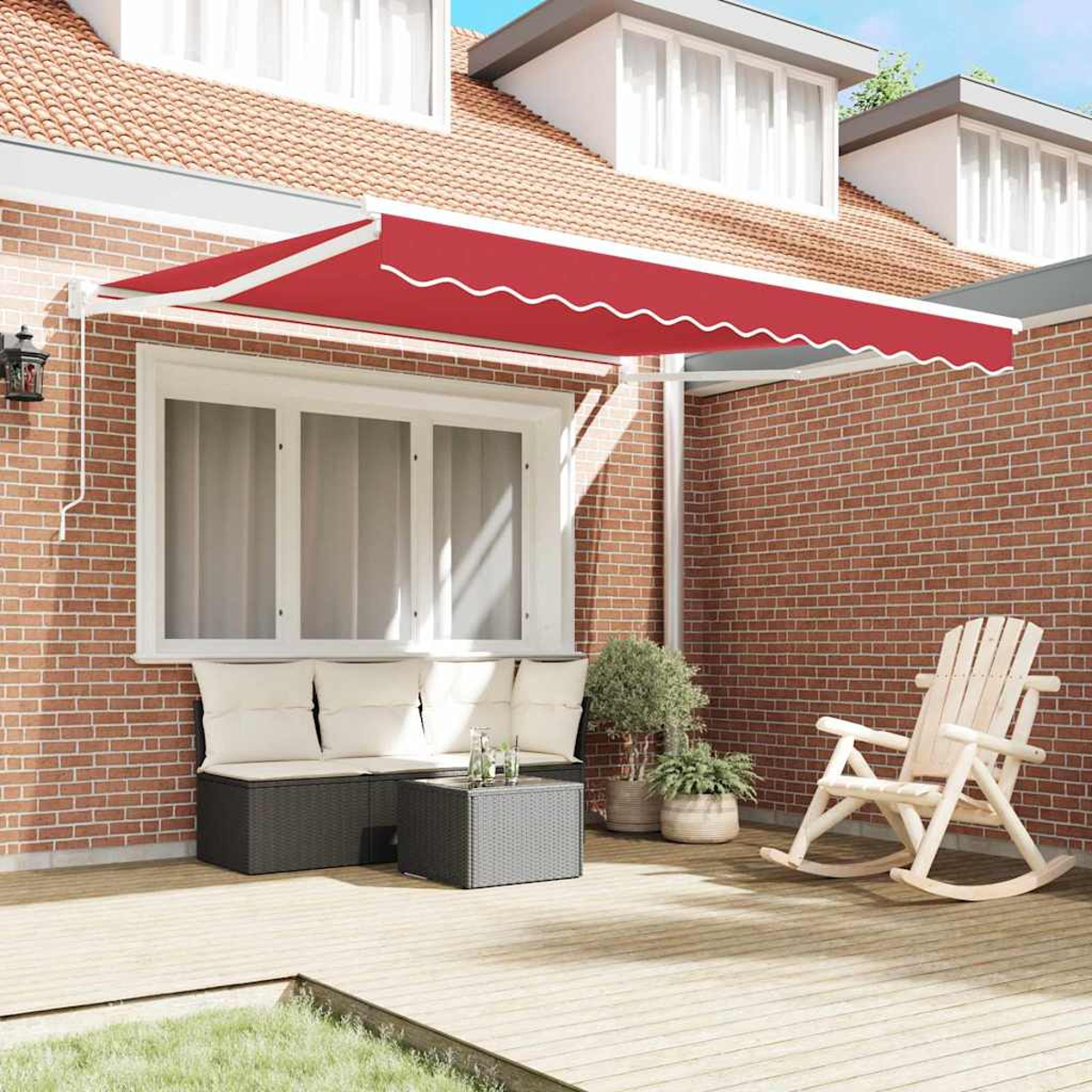 Eine rote Markise bedeckt eine Terrasse mit einer Bank, einem Tisch und einem Schaukelstuhl. Im Hintergrund eine Backsteinmauer und ein Haus mit Fenstern.
