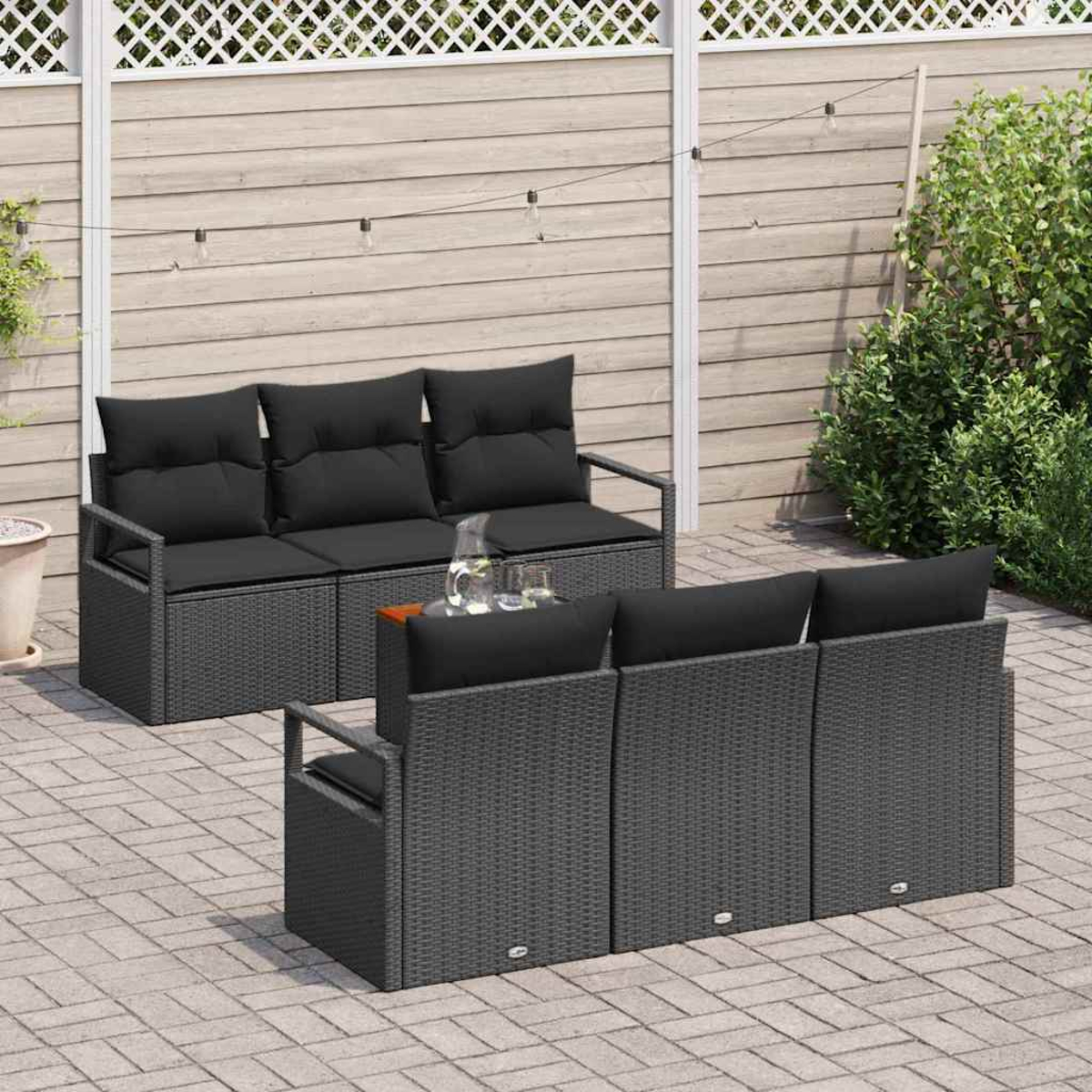 Garten-Terrassenset mit schwarzen Kissen auf grauen Korbmöbeln. Enthält ein Dreisitzer-Sofa und zwei Stühle auf einer Ziegelterrasse.