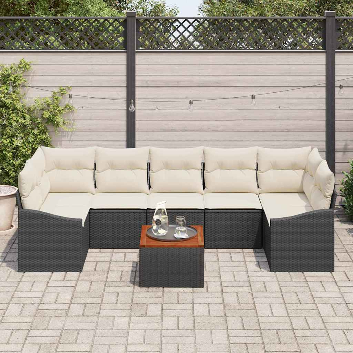 Outdoor-Ecksofa mit cremefarbenen Kissen, einem kleinen Tisch mit Getränken und einem Holzzaun im Hintergrund.
