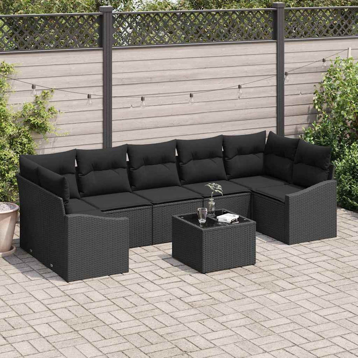 Schwarzes Ecksofa für den Außenbereich mit Kissen und einem kleinen Tisch auf einer Backstein-Terrasse. Im Hintergrund ein Zaun und Grün.