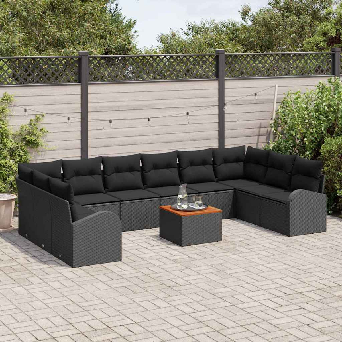 Outdoor-Ecksofa mit schwarzen Kissen, einem Couchtisch und einem Hintergrund mit Zaun und Grün.