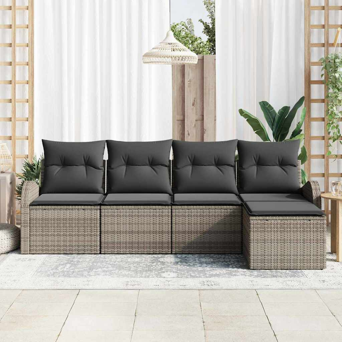 Outdoor-Ecksofa mit grauen Kissen. Geflochtene Basis, weiße Vorhänge und eine gewebte Lampe befinden sich im Hintergrund, zusammen mit Pflanzen.