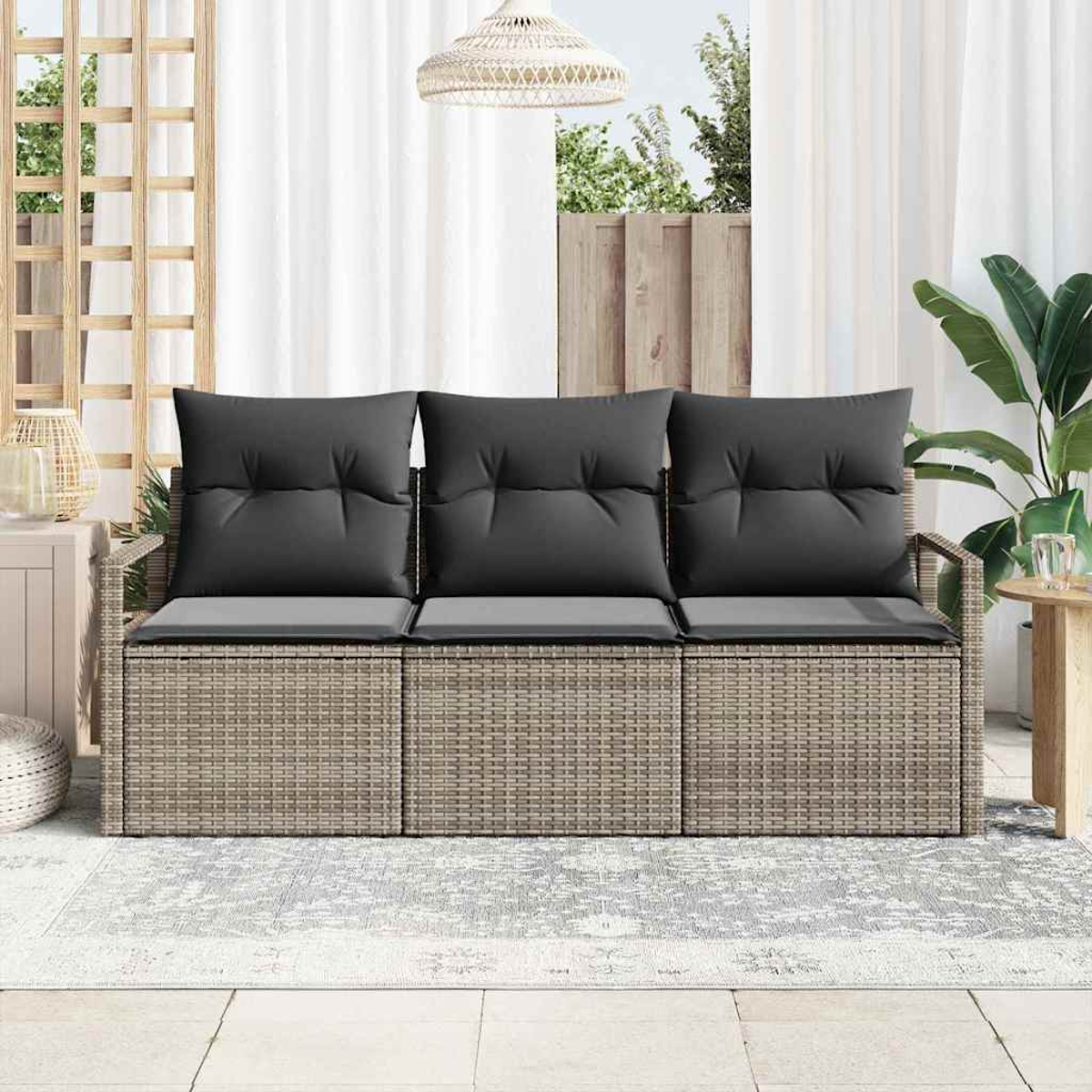 Wicker-Sofa mit schwarzen Kissen, platziert auf einem gemusterten Teppich. Im Hintergrund sind ein weißer Vorhang und eine Pflanze.