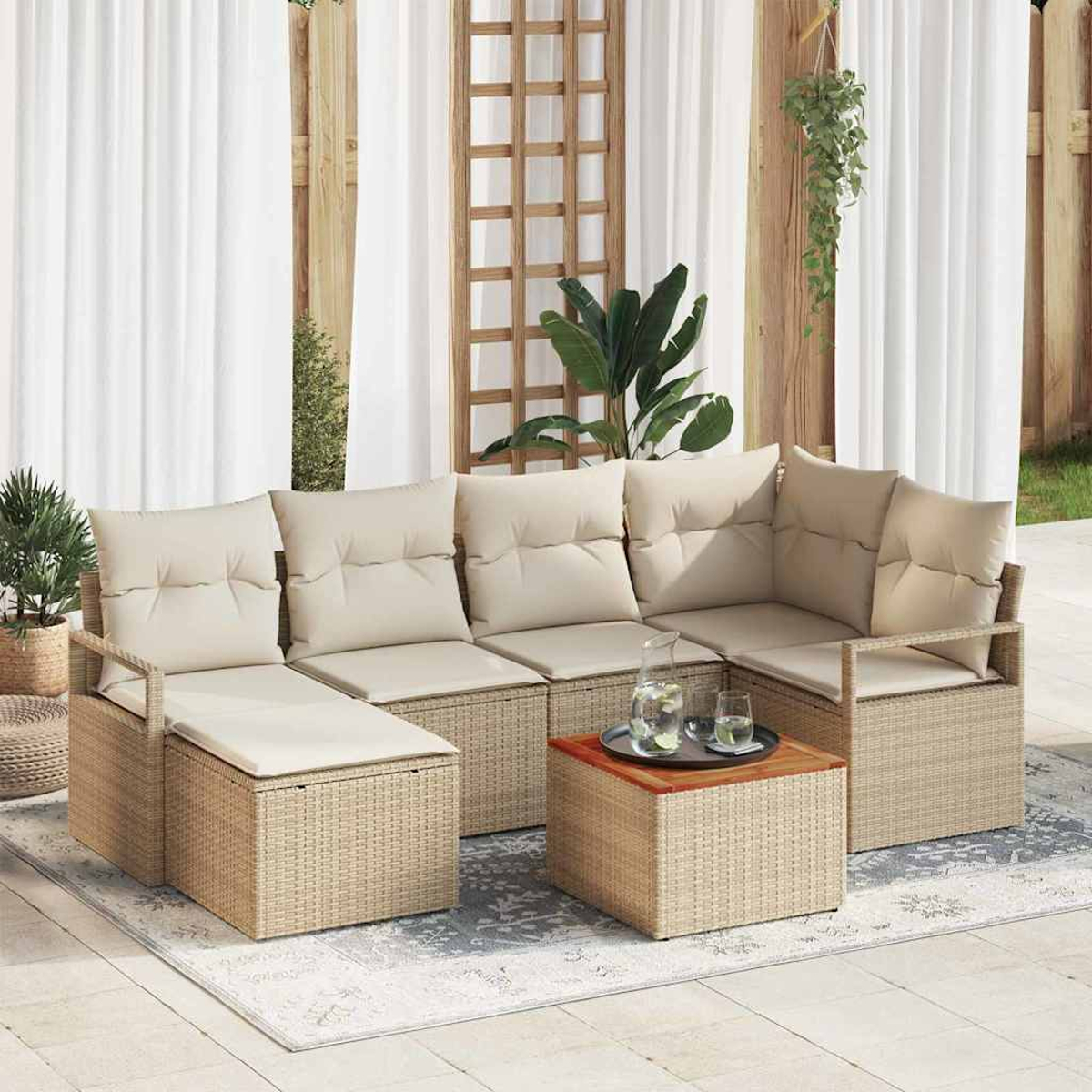 Outdoor-Wickersofa mit beigen Kissen, kleiner Holztisch mit Getränken und Pflanzen im Hintergrund. Weiße Vorhänge und Holzgitter.