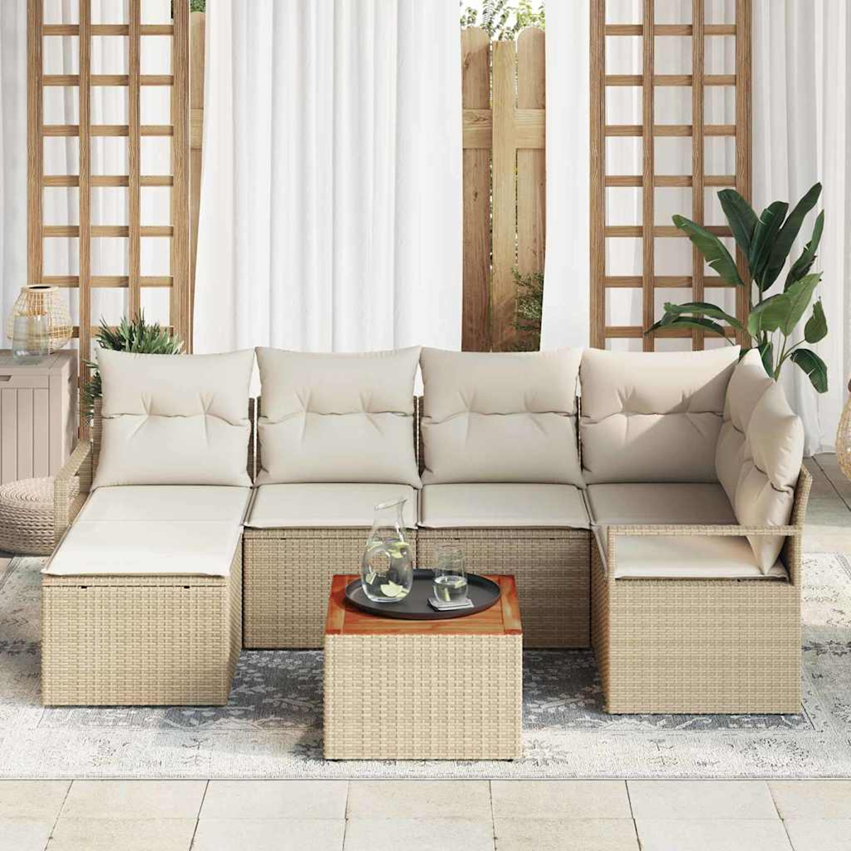 Outdoor-Ecksofa mit cremefarbenen Kissen und Weidenrahmen. Davor steht ein kleiner Tisch mit Getränken. Der Hintergrund umfasst Vorhänge und Pflanzen.