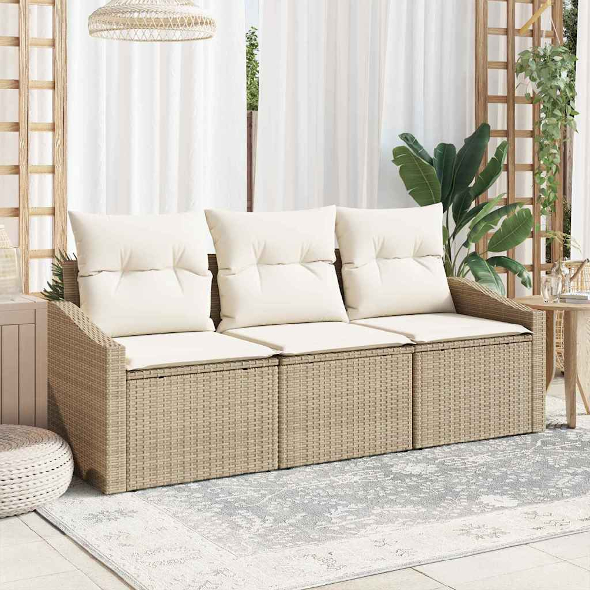 Ein Rattansofa mit cremefarbenen Kissen steht auf einem grauen Teppich. Ein gewebter Lampenschirm hängt darüber. Weiße Vorhänge und Pflanzen sind sichtbar.