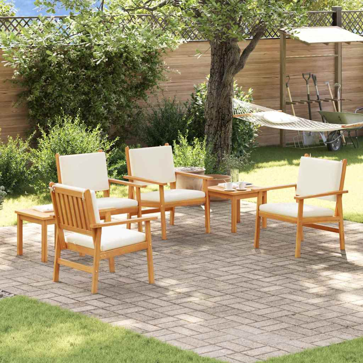 Szene im Freien mit Holzstühlen, einem kleinen Tisch und einer Hängematte im Hintergrund. Beige Kissen auf Stühlen, auf einer Ziegelterrasse.