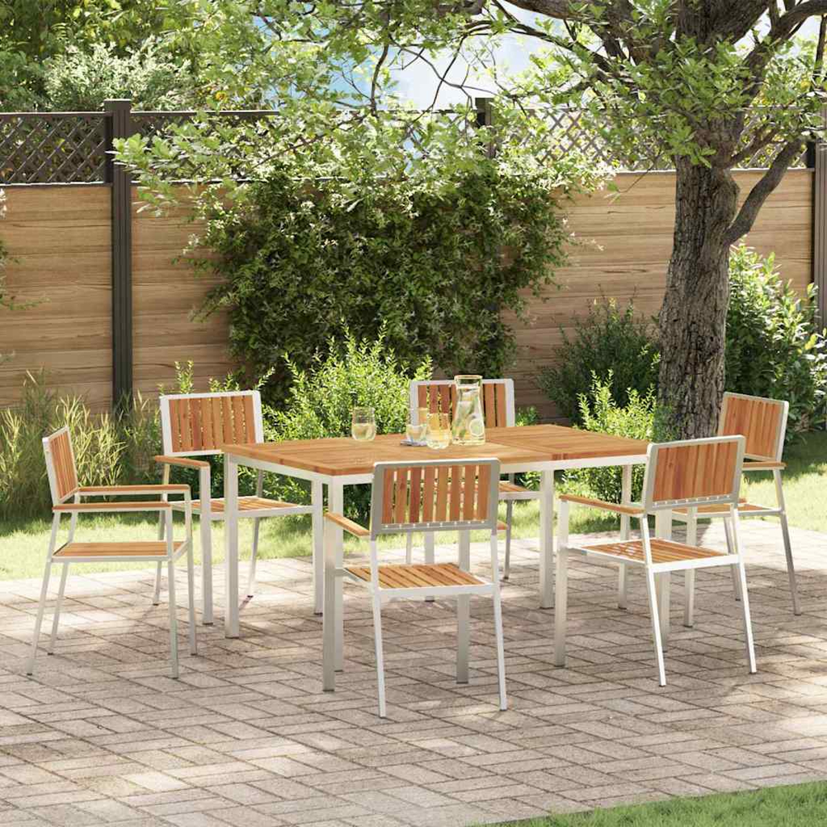 Essgruppe im Freien: quadratischer Holztisch mit sechs Stühlen, auf einer Ziegelterrasse, umgeben von Grün und einem Holzzaun.