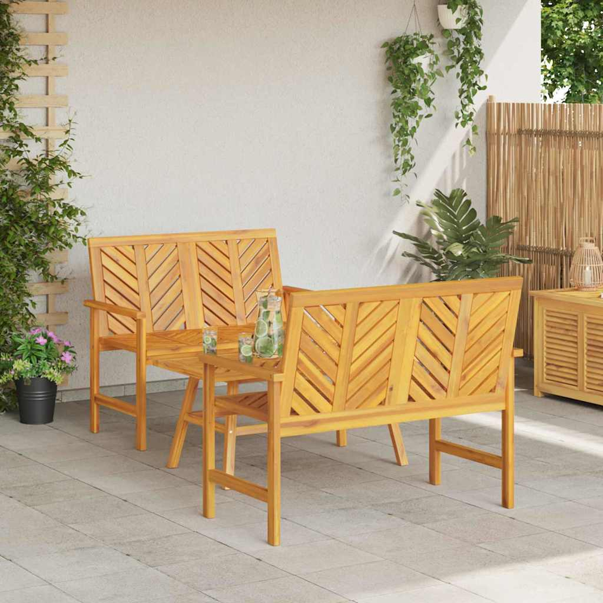 Gartenmöbelset aus Holz: zwei Bänke und ein Tisch. Pflanzen und Holzzaun im Hintergrund, alles auf einer Terrasse.