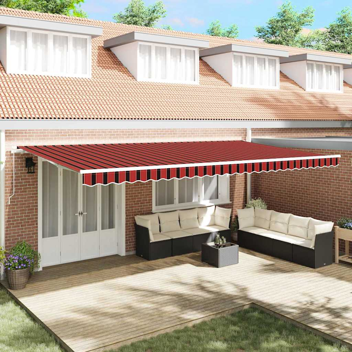 Ein Haus mit gestreifter Markise, Sofas und einem kleinen Tisch auf einer Holzterrasse. Ziegelmauer und grünes Gras im Vordergrund.