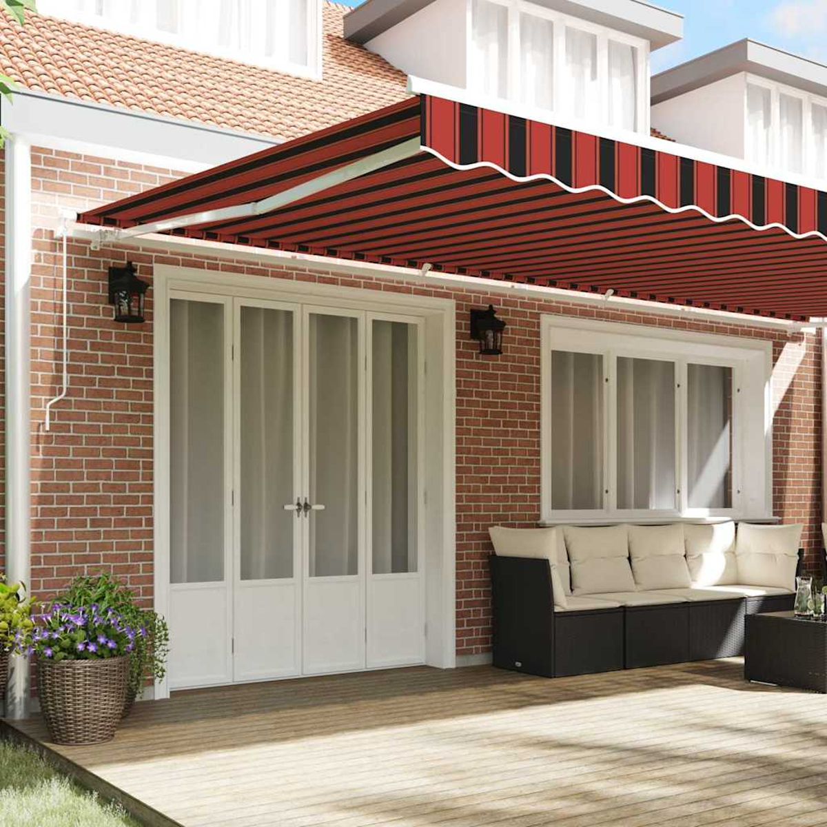 Ein Haus mit einer rot-schwarz gestreiften Markise. Weiße Türen und Fenster. Ein brauner Weidenkorb mit lila Blumen.