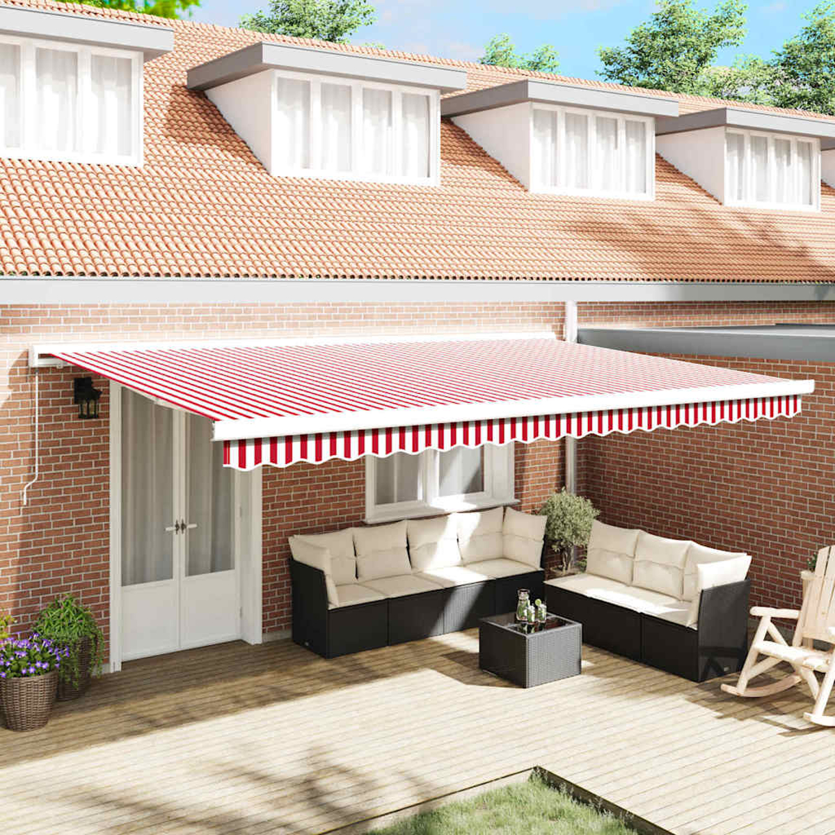 Eine Terrasse mit rot-weiß gestreifter Markise, Sitzgelegenheiten und einer Backsteinmauer. Im Hintergrund ein Haus mit Ziegeldach.