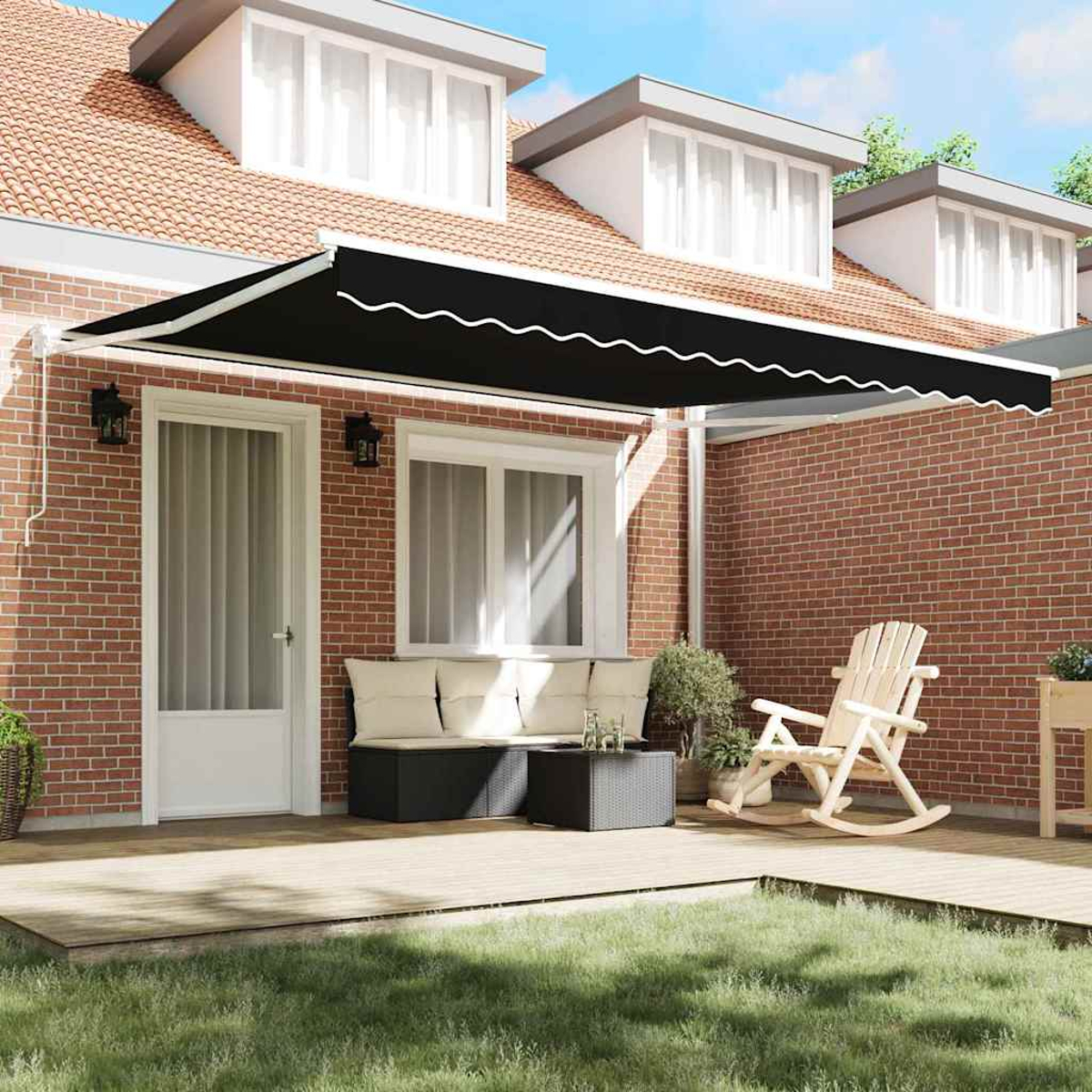 Eine Terrasse mit schwarzer Markise, Ziegelmauer und Rasen. Es gibt eine weiße Tür, eine Bank, einen Schaukelstuhl und einen Tisch.