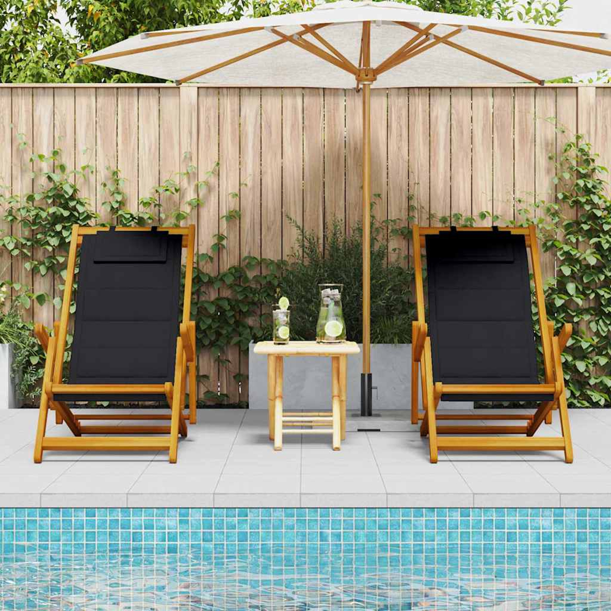 Zwei schwarze Liegestühle, ein kleiner Tisch mit Getränken und ein Sonnenschirm stehen an einem Pool. Im Hintergrund sind ein Holzzaun und Pflanzen.