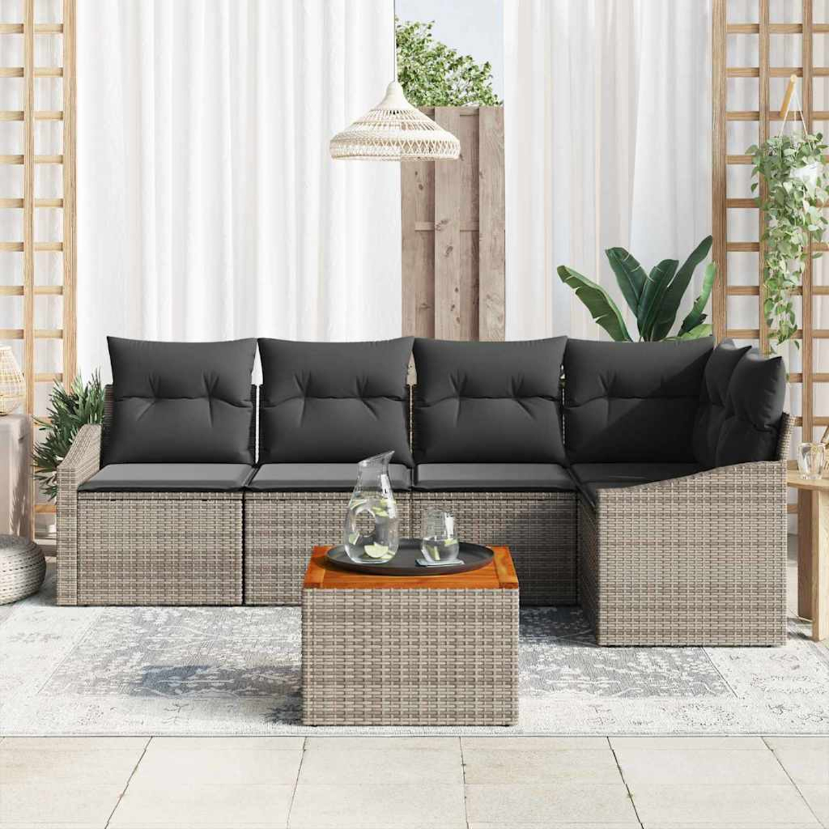 Outdoor-Terrassenset mit grauen Kissen, einem Holztisch mit Getränken und einem weißen Vorhang als Hintergrund.