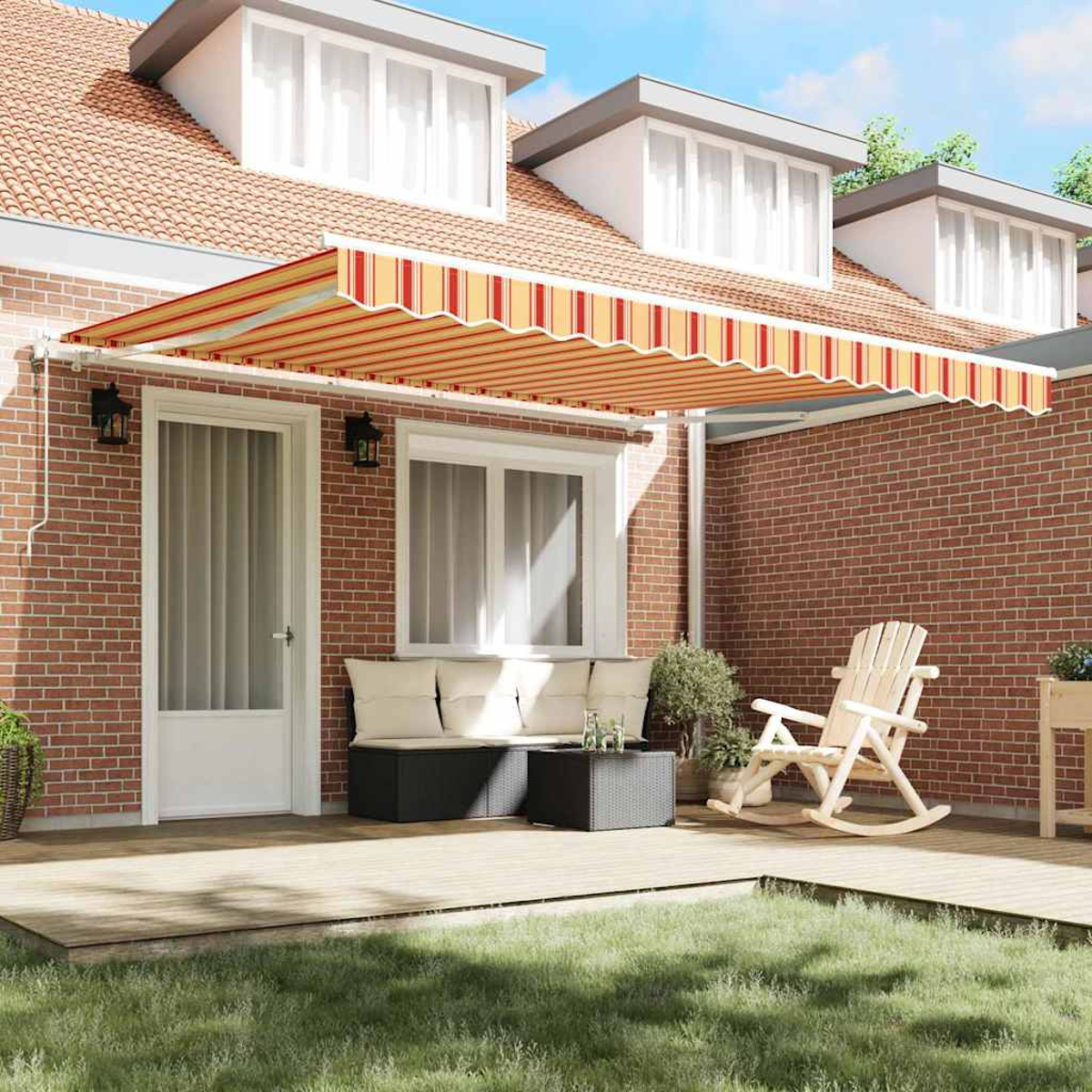 Ein Haus mit gestreifter Markise, Terrasse mit Möbeln, Schaukelstuhl und Rasen.