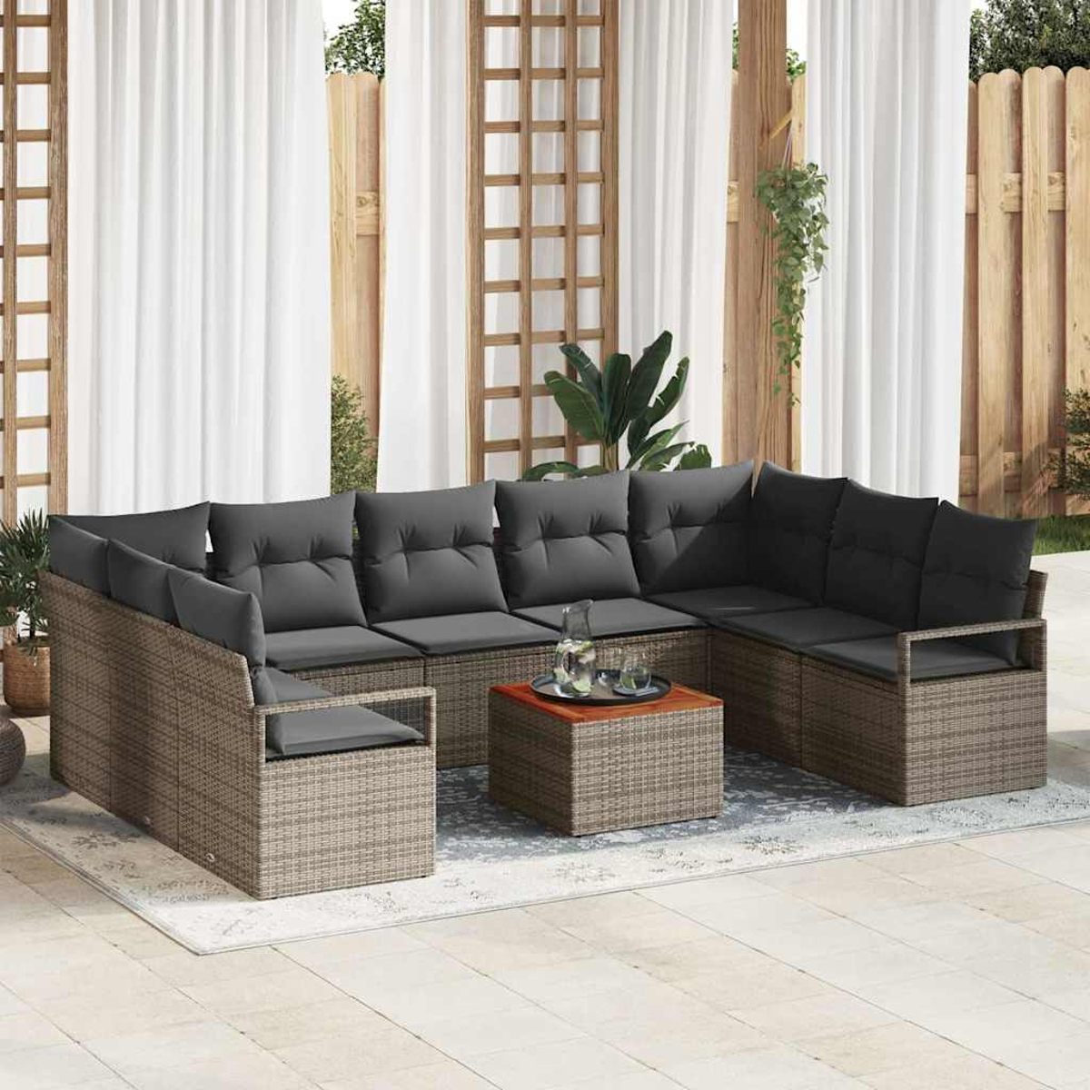Outdoor-Ecksofa mit grauen Kissen und einem kleinen Tisch mit Getränken. Weiße Vorhänge und Holzzaun im Hintergrund.