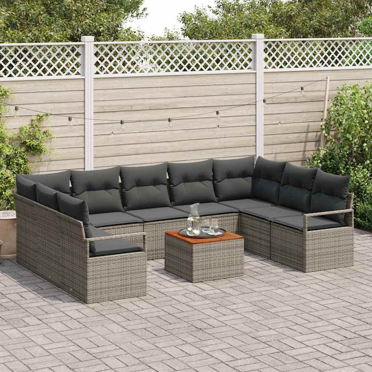 Outdoor-Ecksofa mit dunkelgrauen Kissen und einem quadratischen Tisch auf einer Steinterrasse, dahinter ein Zaun und Grün.