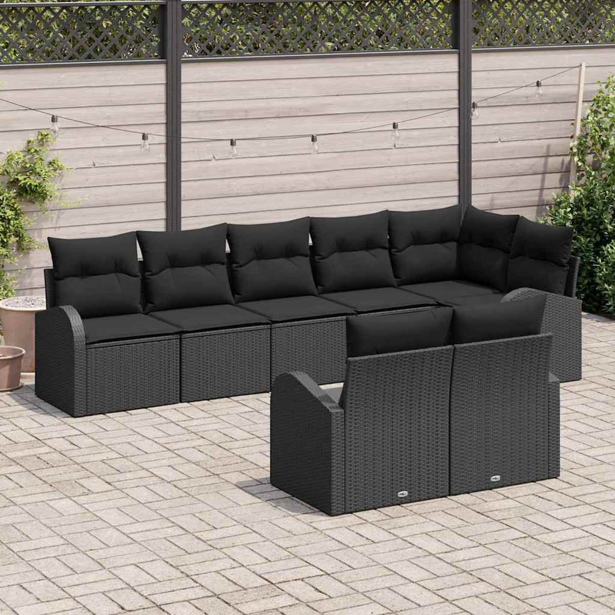 Gartenmöbel-Set: ein großes schwarzes Ecksofa und zwei Stühle auf einer Ziegelterrasse. Holzzaun und Pflanzen im Hintergrund.