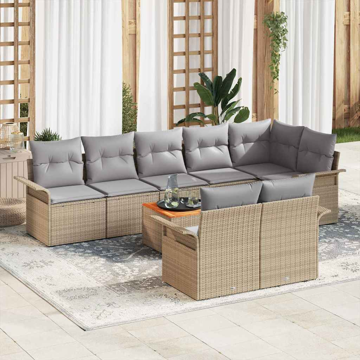 Gartenmöbel-Set. Beiges Korbmöbel-Sofa mit grauen Kissen, Couchtisch und Teppich. Weiße Vorhänge und Pflanzen im Hintergrund.