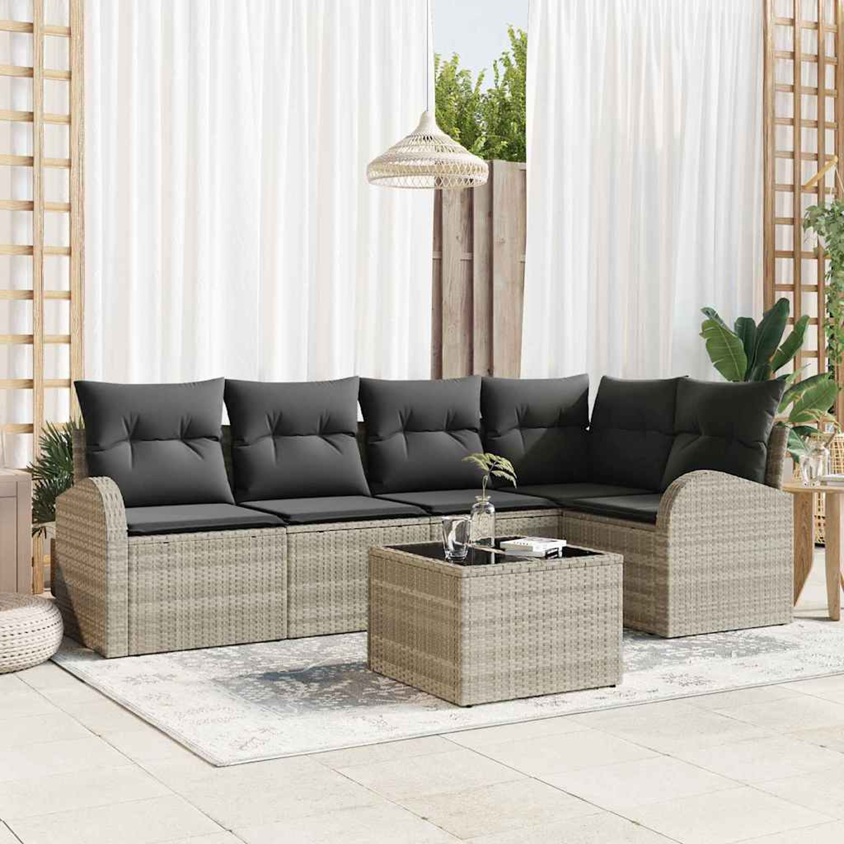 Garten-Sitzgruppe mit grauen Kissen, einem Couchtisch und weißen Vorhängen. Die Szene ist hell und luftig.