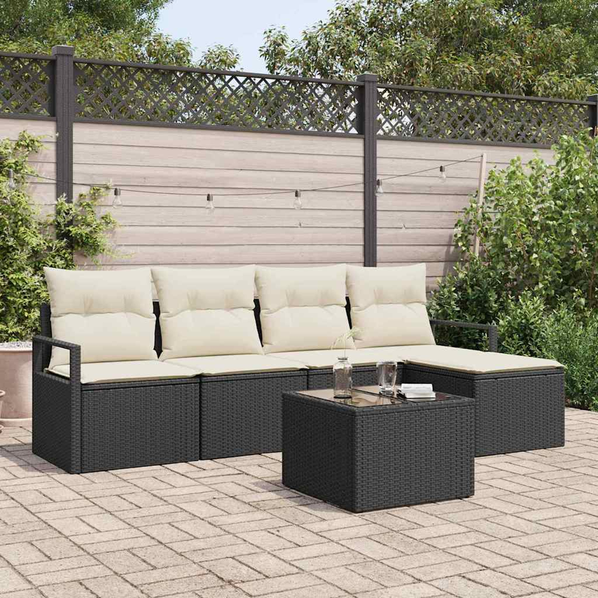 Garten-Sitzgruppe mit schwarzem Korbgeflecht und cremefarbenen Kissen, ein Tisch mit Glasplatte, auf einer Backstein-Terrasse. Im Hintergrund ein Holzzaun.