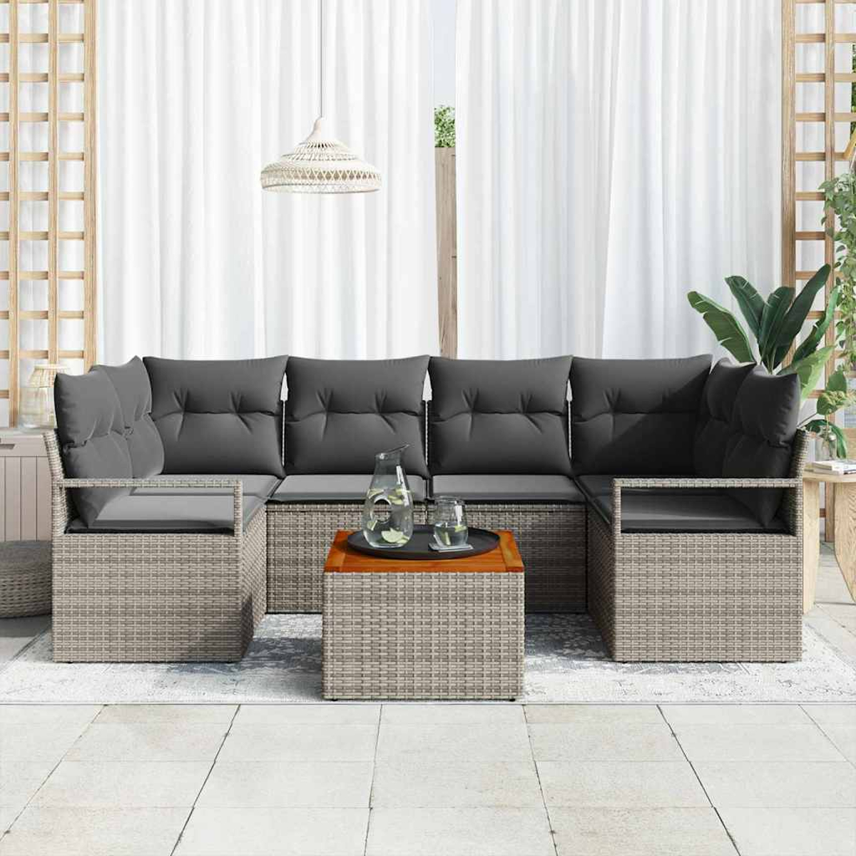 Outdoor-Ecksofa mit grauen Kissen, kleiner Tisch mit Getränken und weißen Vorhängen im Hintergrund.