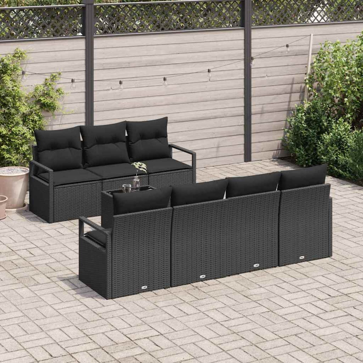 Garten-Terrassenset mit schwarzen Kissen und Korbgewebe. Enthält ein Dreisitzer-Sofa und ein Ecksofa auf einer gepflasterten Terrasse.