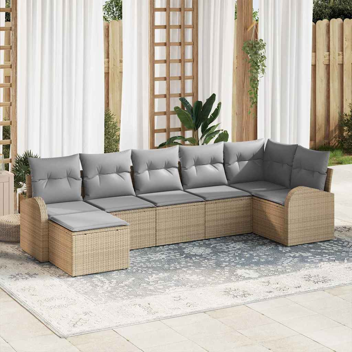 Ein Ecksofa im Freien mit grauen Kissen steht auf einem Teppich. Weiße Vorhänge und ein Holzzaun sind im Hintergrund.