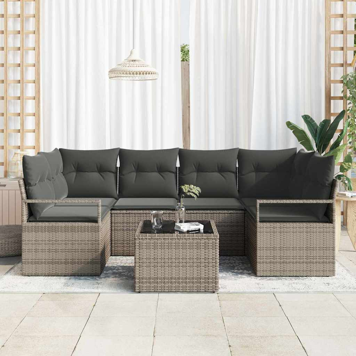 Outdoor-Ecksofa mit dunkelgrauen Kissen, einem quadratischen Tisch und weißen Vorhängen im Hintergrund. Eine Hängelampe ist oben.