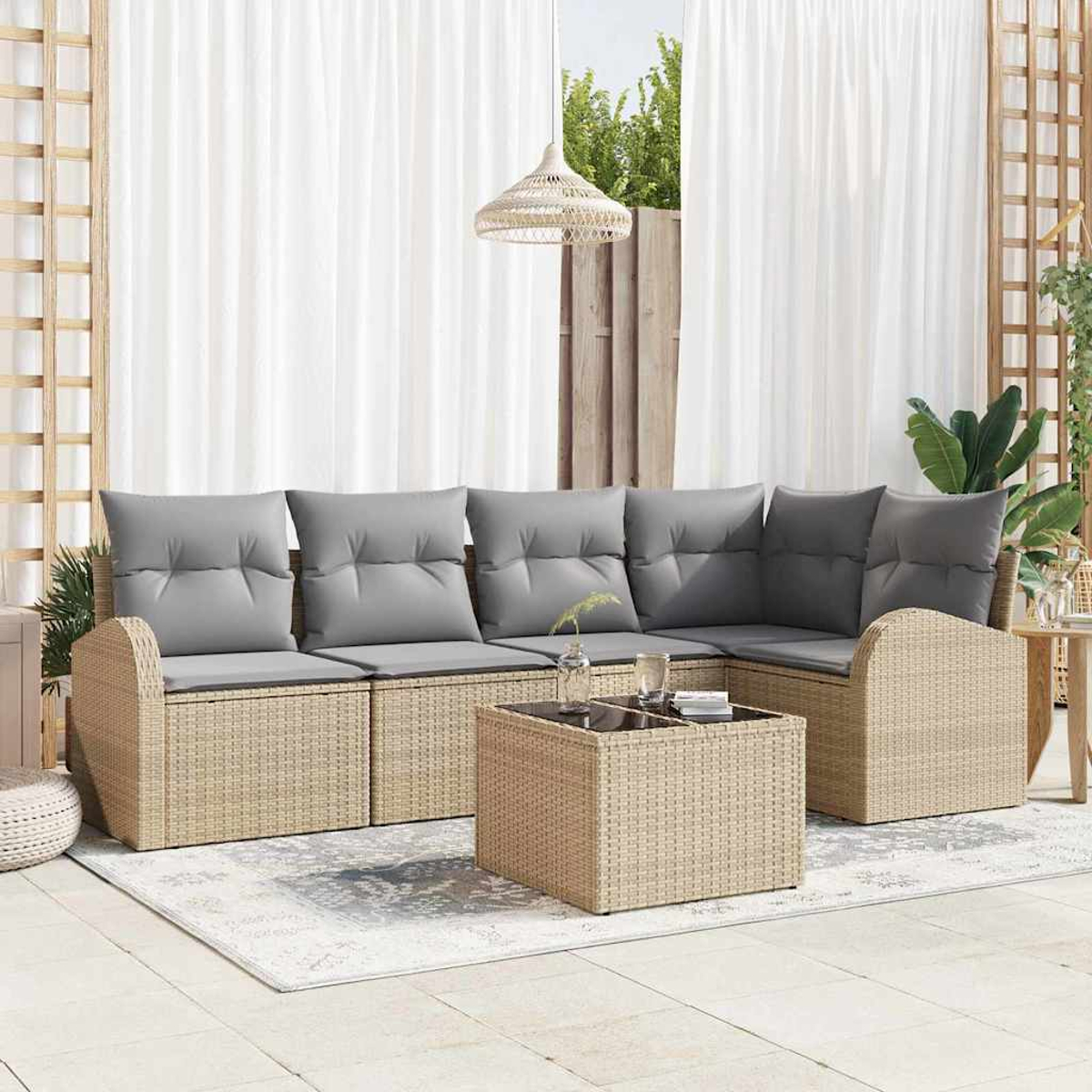 Rattan-Sofa im Freien mit grauen Kissen, einem Couchtisch und weißen Vorhängen. Eine gewebte Lampe hängt darüber. Hintergrund mit Grün.