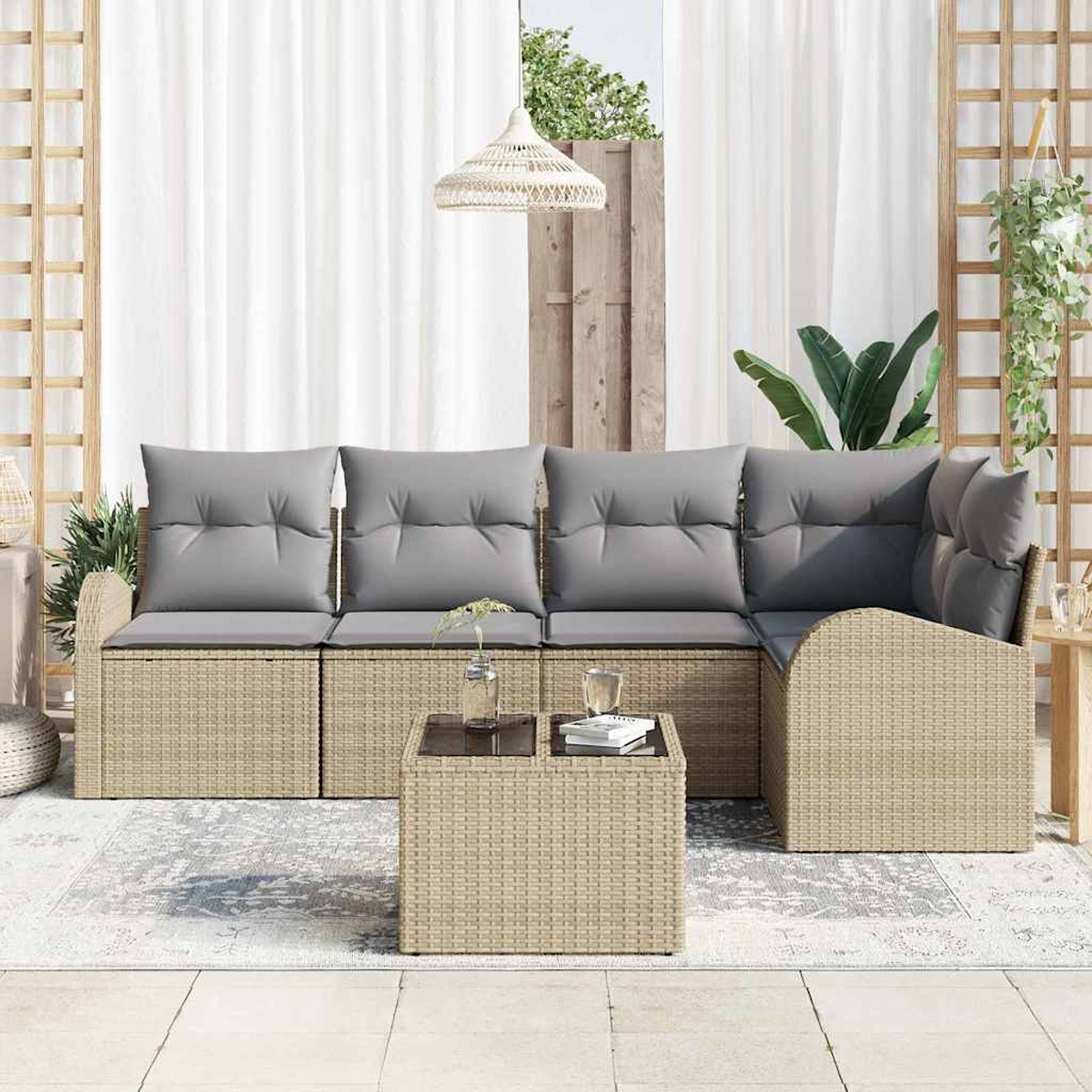Outdoor-Korbsessel mit grauen Kissen und einem kleinen Tisch. Der Hintergrund hat weiße Vorhänge und einige Pflanzen.