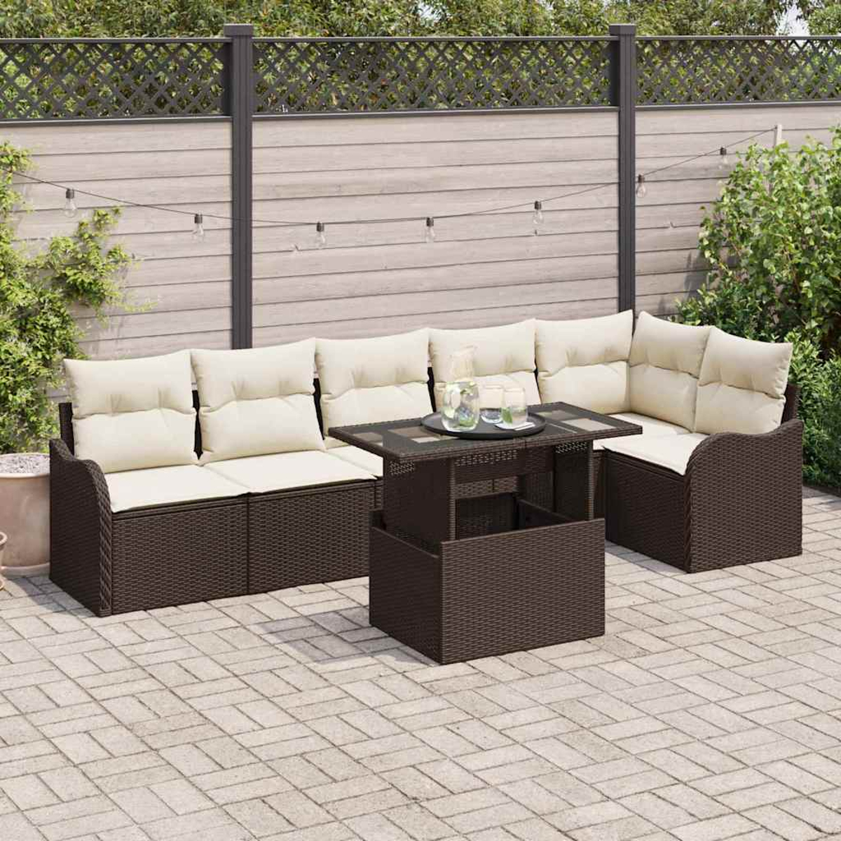 Garten-Sitzgruppe mit Kissen und einem Tisch auf einer Terrasse. Dunkelbraune Korbmöbel, beige Kissen und ein Tisch mit Glasplatte.