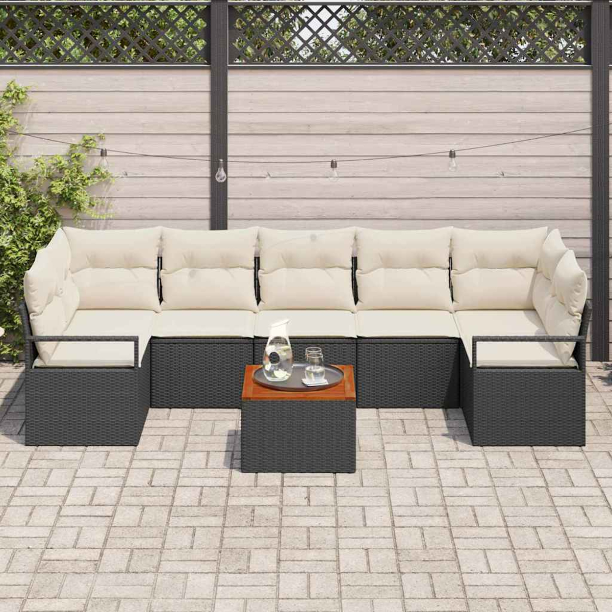 Outdoor-Ecksofa mit cremefarbenen Kissen, einem kleinen Tisch mit einem Tablett mit Getränken und einem dekorativen Holzzaun.
