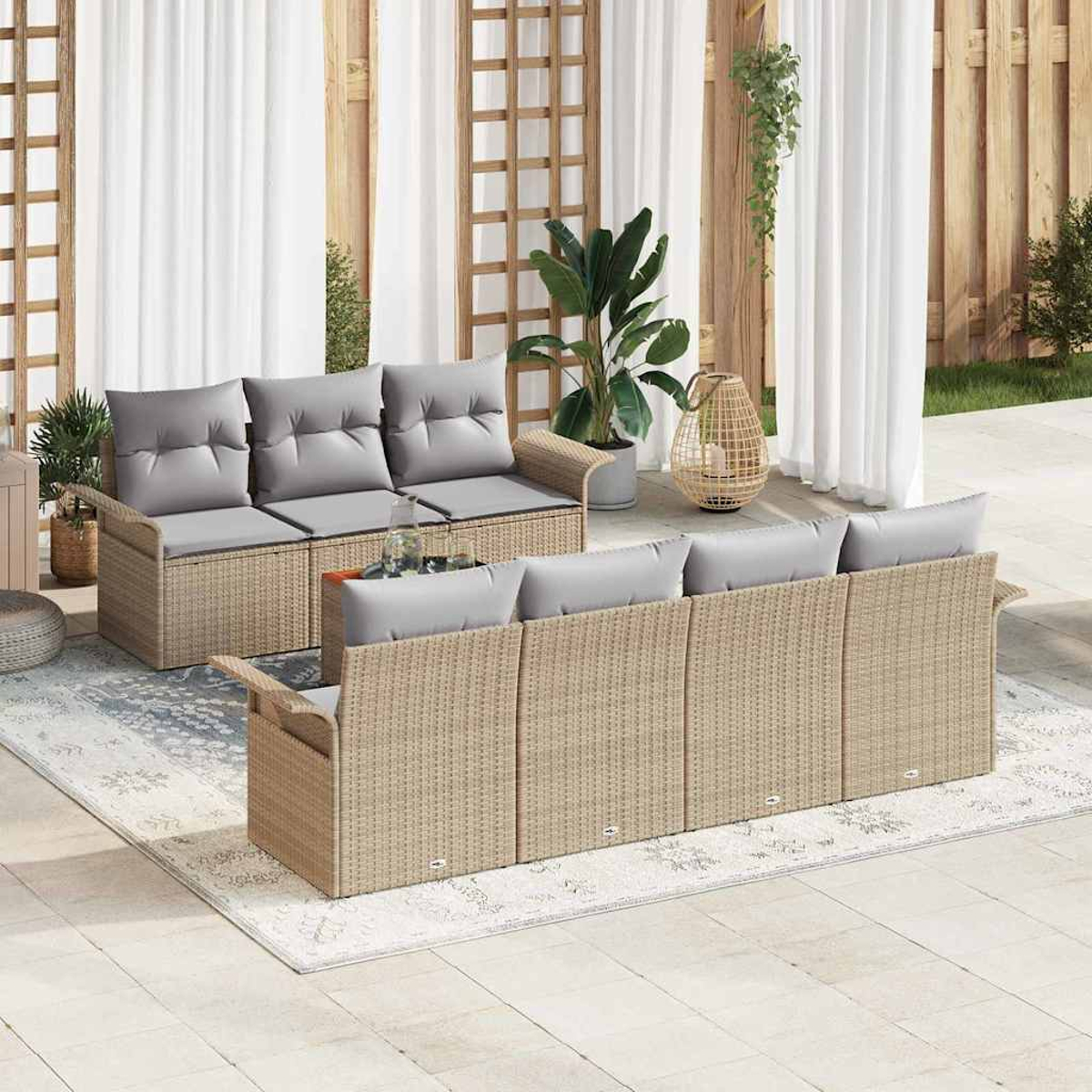 Garten-Terrassenset mit beigen Korbsesseln, grauen Kissen und einem Tisch mit Glasplatte. Weiße Vorhänge und Pflanzen im Hintergrund.