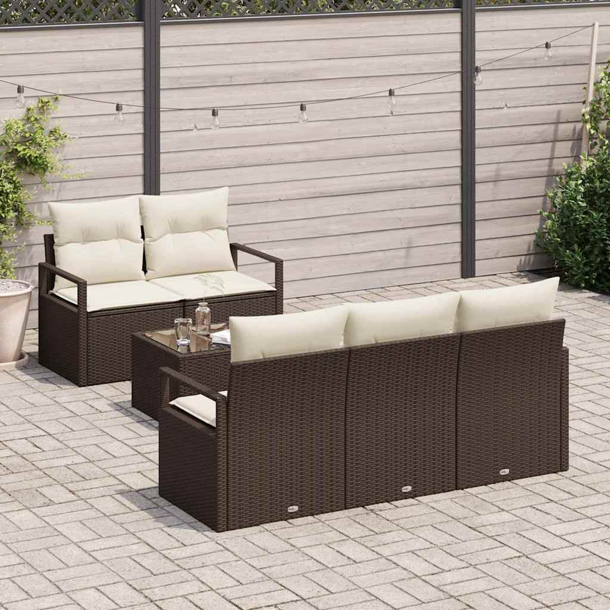 Gartenmöbel-Set, braunes Korbgeflecht mit cremefarbenen Kissen, auf einer Steinterrasse. Enthält ein Sofa, einen Tisch und einen Stuhl.